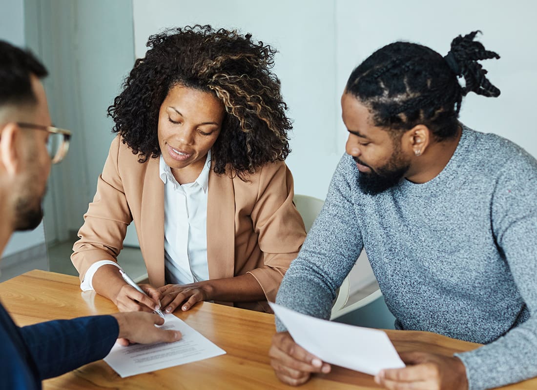 About Our Agency - Couple Signing Paperwork With Their Agent