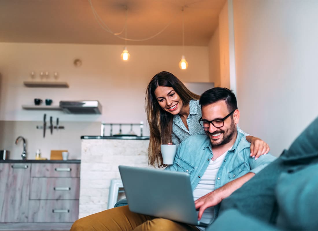 Service Center - Young Couple Using a Laptop While Sitting on the Sofa at Home